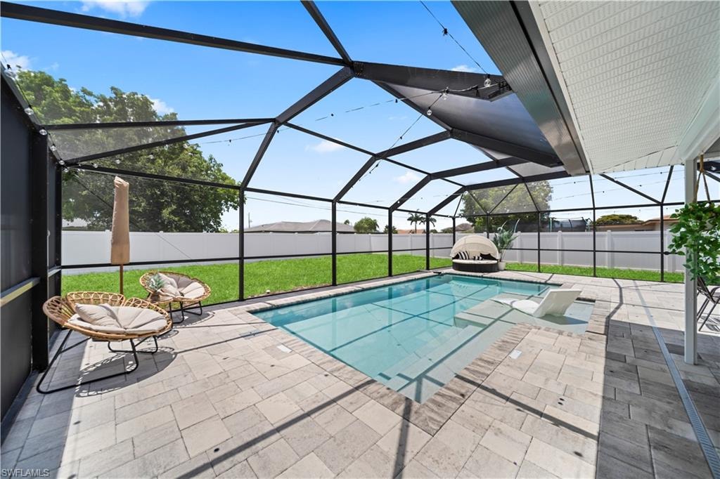 Screened enclosure featuring an in-ground swimming pool with an integrated sun shelf and surrounding paver patio