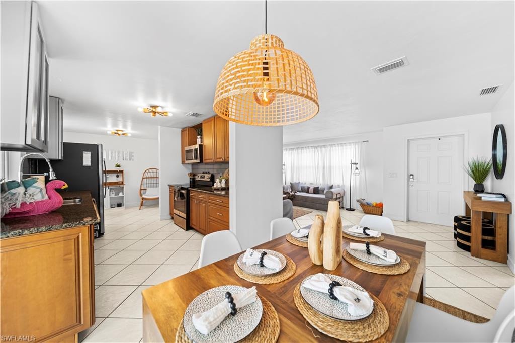 Dining area featuring a wood-finish table, overhead woven pendant light fixture, and tile flooring