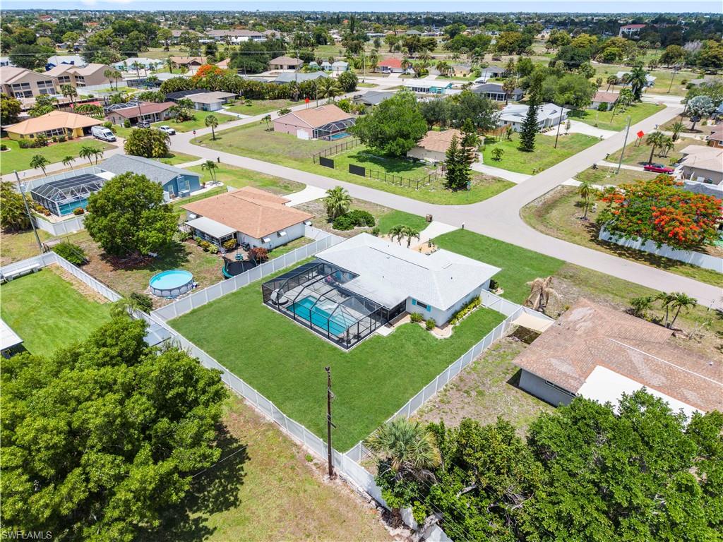 Property featuring a screened-in swimming pool, white perimeter fencing, and a manicured lawn