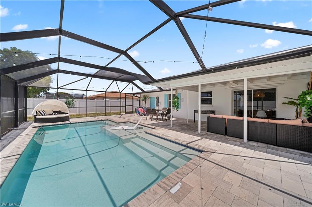 Screened outdoor living area featuring a rectangular pool with integrated steps, a covered patio, and paver decking
