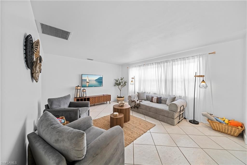 Spacious living area featuring light-colored tile flooring and white walls