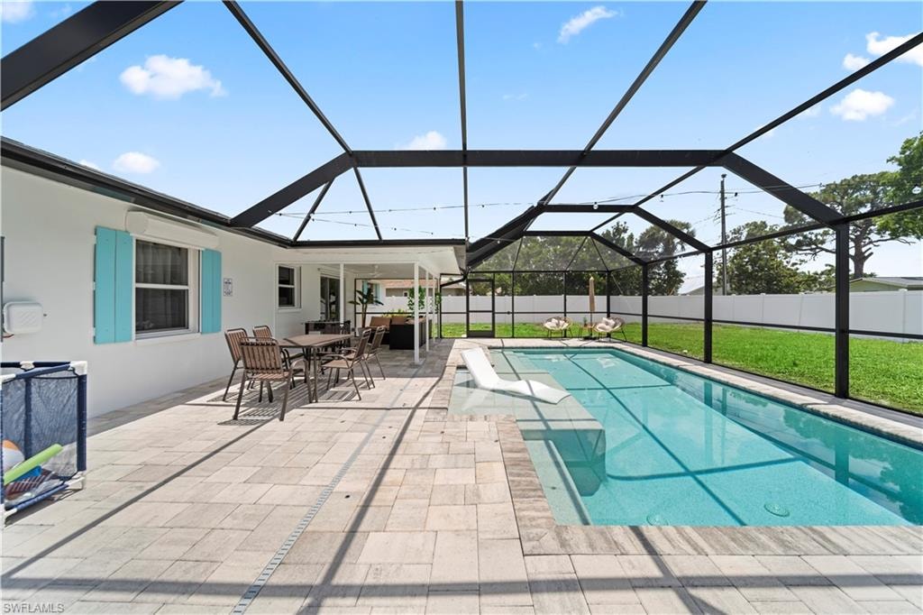 Screened-in outdoor living space featuring an inground swimming pool with integrated spa and diving board, surrounded by stone paver decking