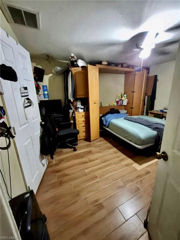 Room featuring wood-look tile flooring, a ceiling fan, and a built-in storage unit with cabinetry