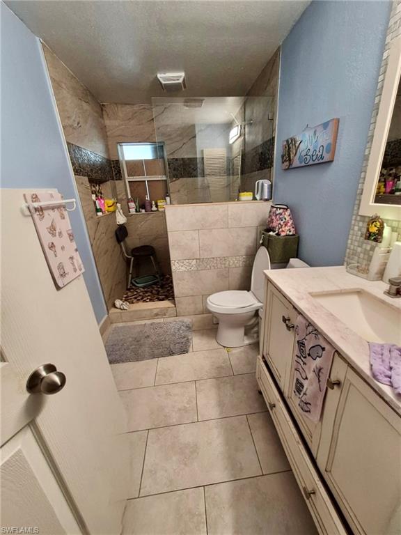 Bathroom featuring a walk-in shower with glass enclosure, toilet, and a vanity with an integrated sink