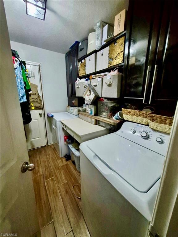 Laundry area featuring wood-finish flooring, dark cabinetry, and built-in shelving