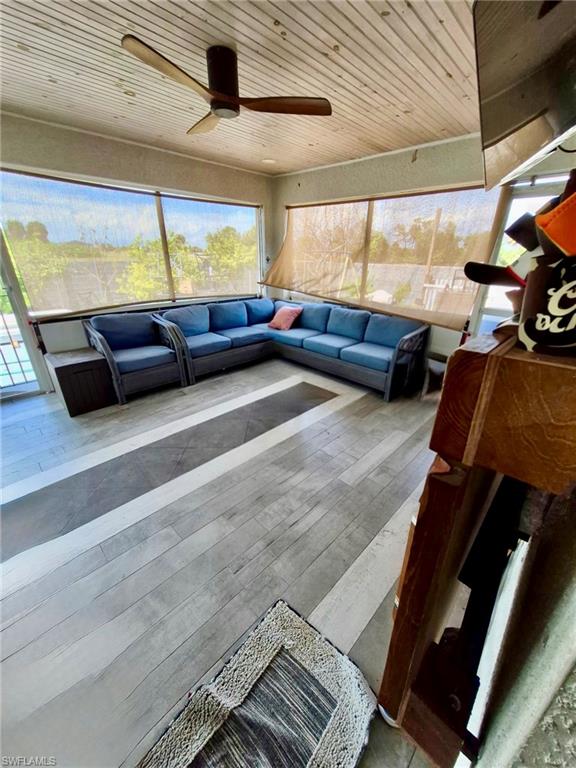 Screened-in porch featuring a wood-finish plank ceiling, a ceiling fan with wooden blades, and large windows with roll-down blinds
