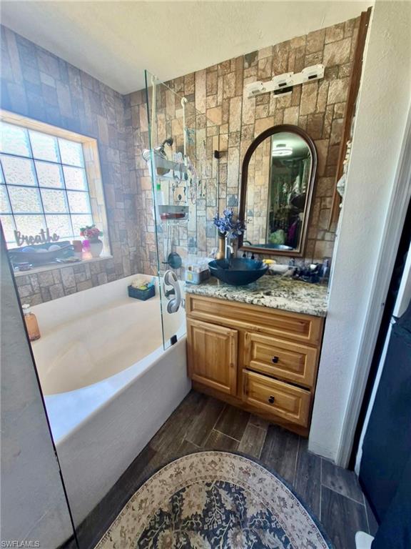 Bathroom featuring a wood vanity with a granite-style countertop and vessel sink