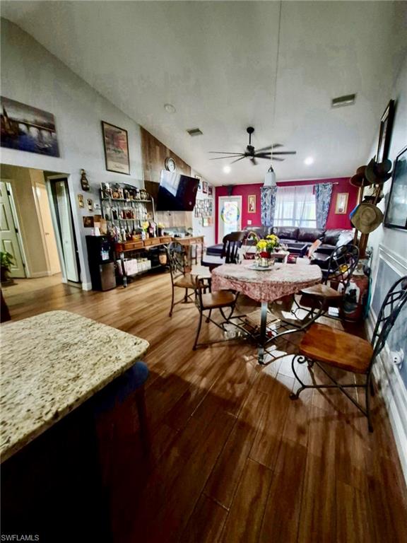 Vaulted ceiling with a ceiling fan, wood-finish flooring, and a granite countertop