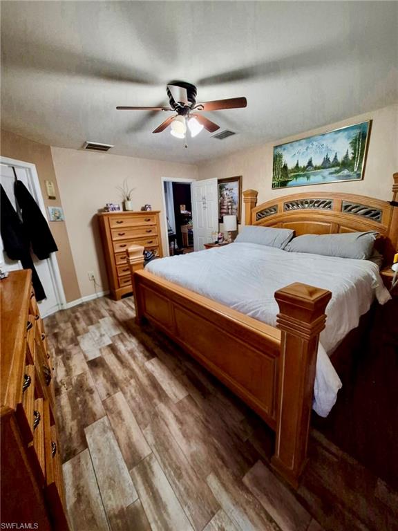 Room featuring wood-finish flooring, a ceiling fan with integrated lighting, and neutral wall paint