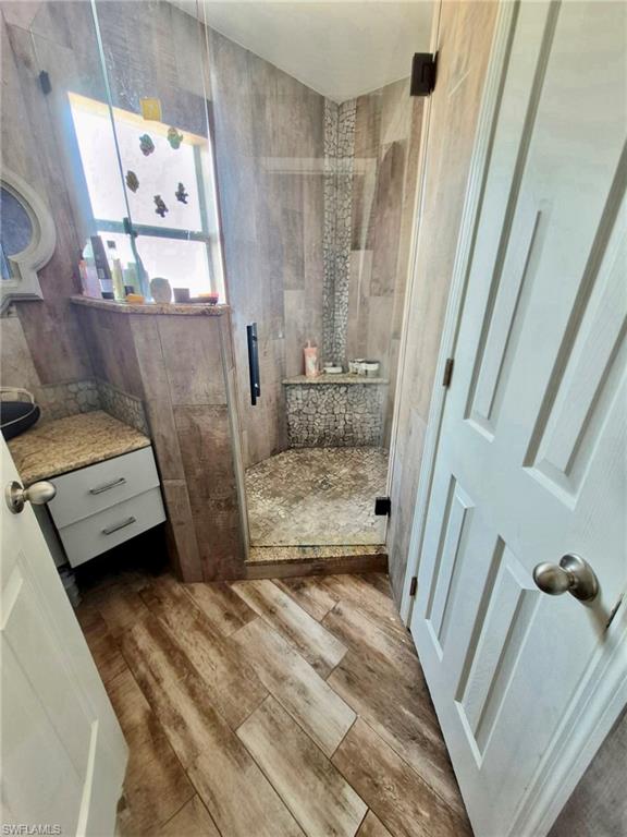 Walk-in shower with clear glass enclosure, mosaic tile floor, and built-in bench