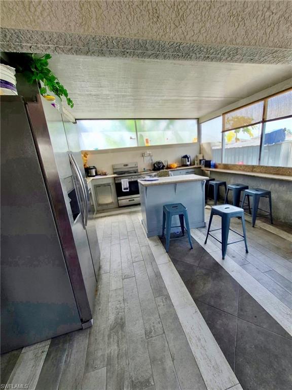 Kitchen featuring two-tone wood-finish flooring, a central island with countertop, and perimeter windows