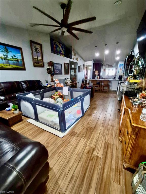 Open-concept living space featuring wood-finish flooring, a large ceiling fan with multiple blades, and recessed lighting
