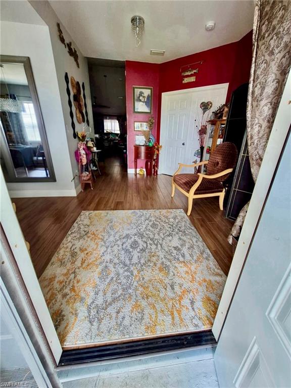 Entryway featuring wood-finish flooring, a white paneled door, and a decorative pendant light fixture