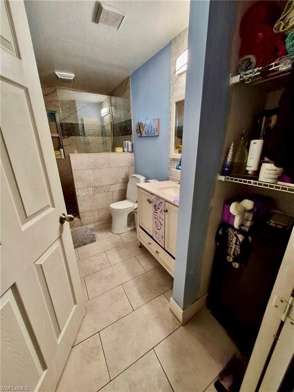 Bathroom featuring a glass-enclosed shower, a vanity with cabinet storage, tile flooring, and integrated wall shelving
