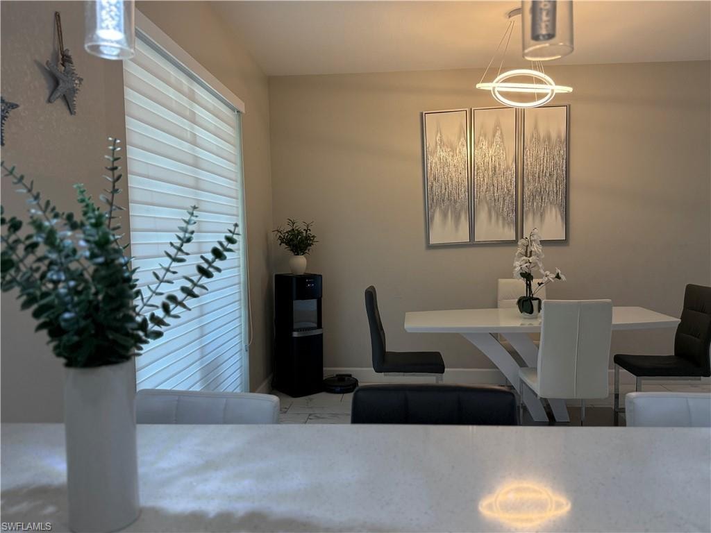 Dining area with a contemporary circular pendant light fixture and three abstract wall art pieces