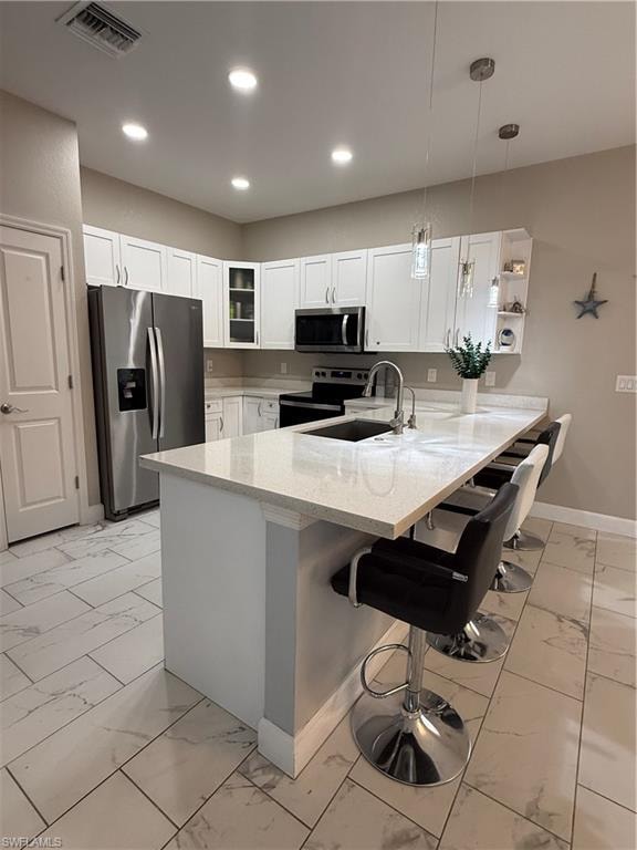 Kitchen featuring an expansive island with a light-toned countertop, white cabinetry, stainless steel appliances, and large format tile flooring