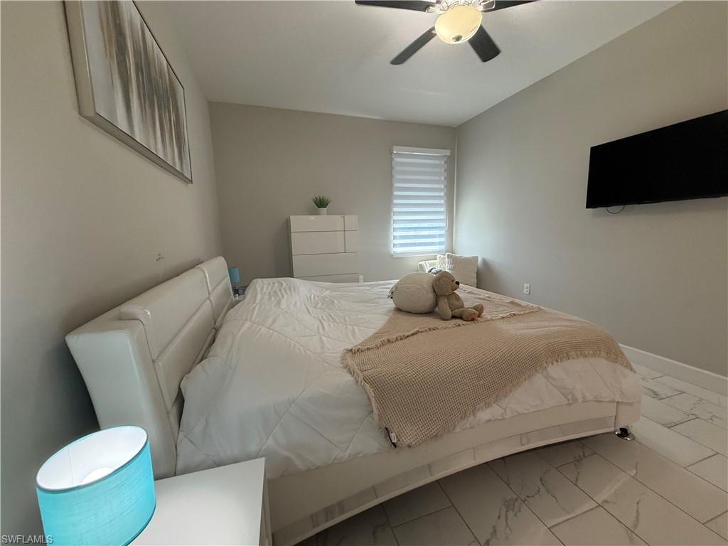 Light-filled room featuring white tile flooring, neutral wall paint, and a ceiling fan with integrated lighting