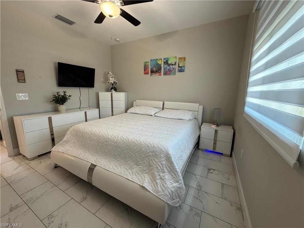 Spacious room featuring light-toned walls, a ceiling fan, and large windows with horizontal blinds