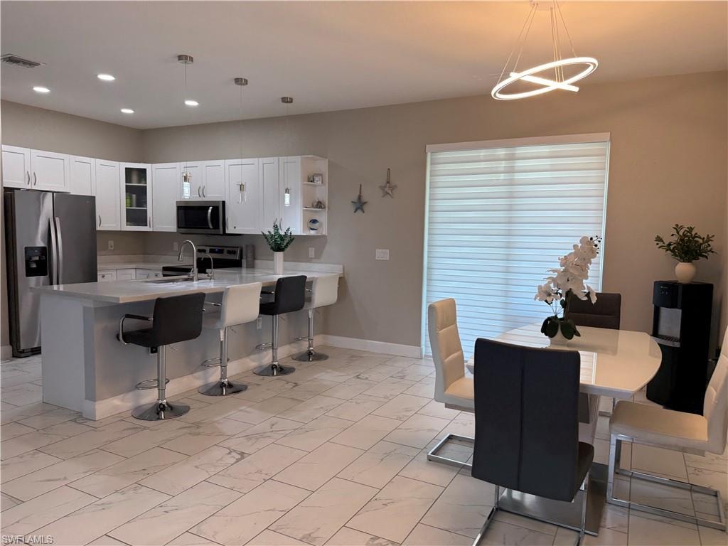 Open-concept kitchen and dining area featuring white shaker cabinetry, stainless steel appliances, and a central island with countertop seating