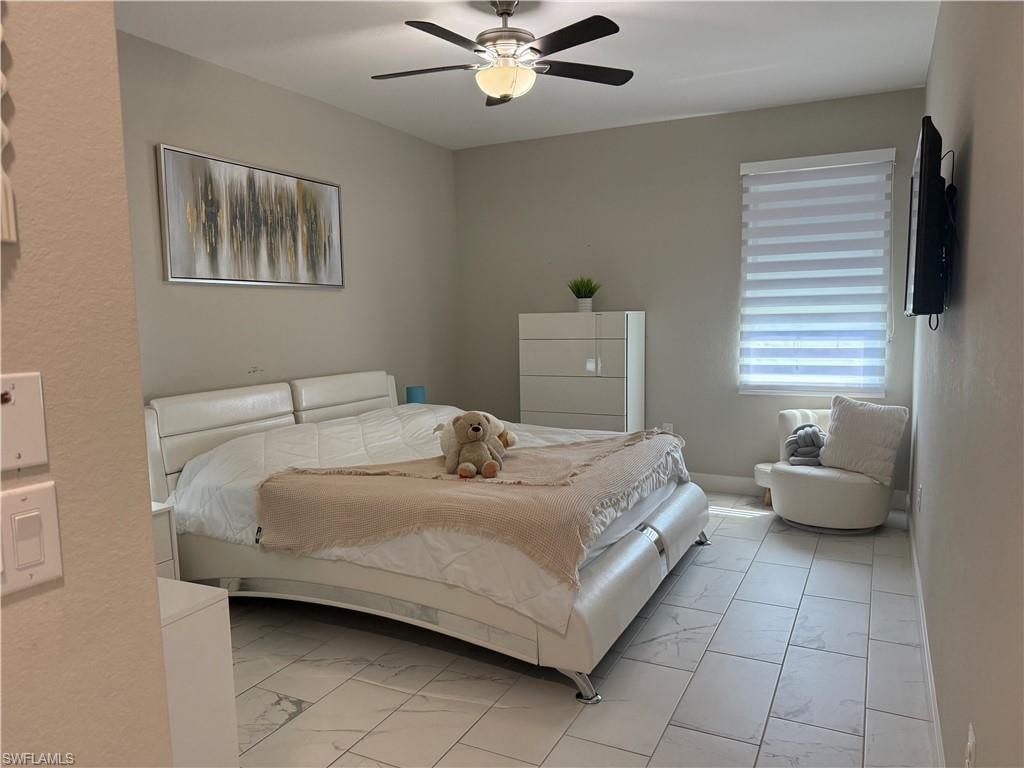 Spacious interior featuring marble-look tile flooring, neutral wall tones, a ceiling fan with integrated lighting, and a window with horizontal blinds
