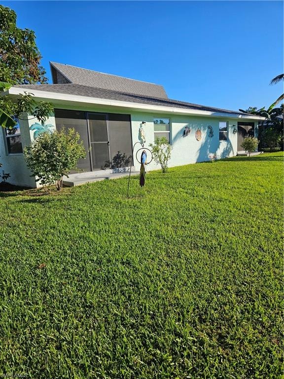 Rear view of house featuring a sunroom and a lawn