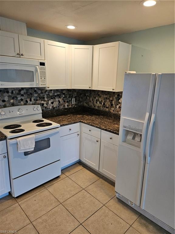 Kitchen with backsplash, light tile patterned floors, range, white cabinetry, and fridge