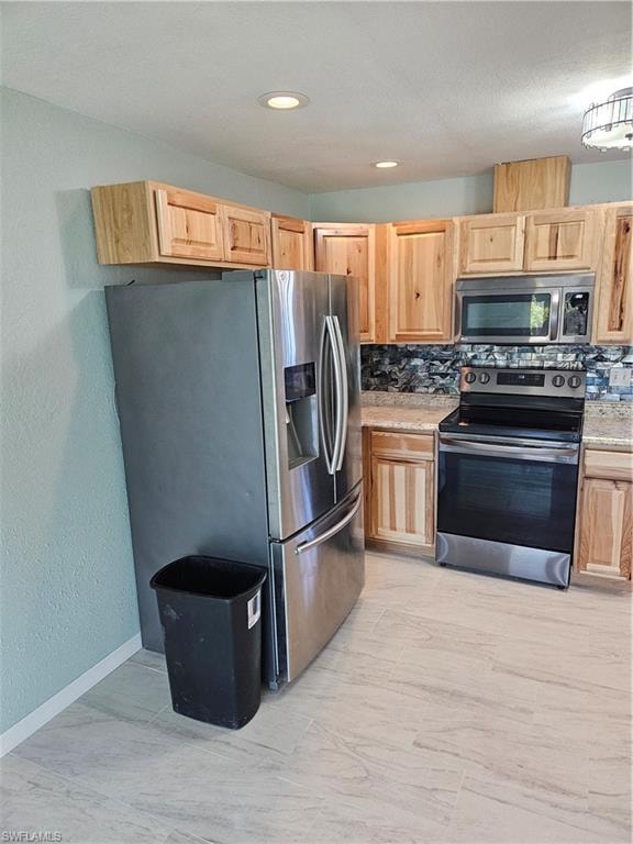 Kitchen featuring stainless steel fridge with ice dispenser, light brown cabinets, range, and backsplash