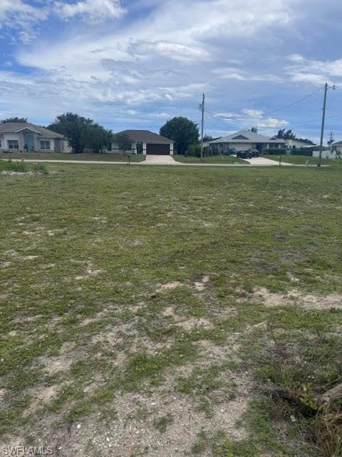 Expansive undeveloped land parcel featuring scattered vegetation and a clear sky above