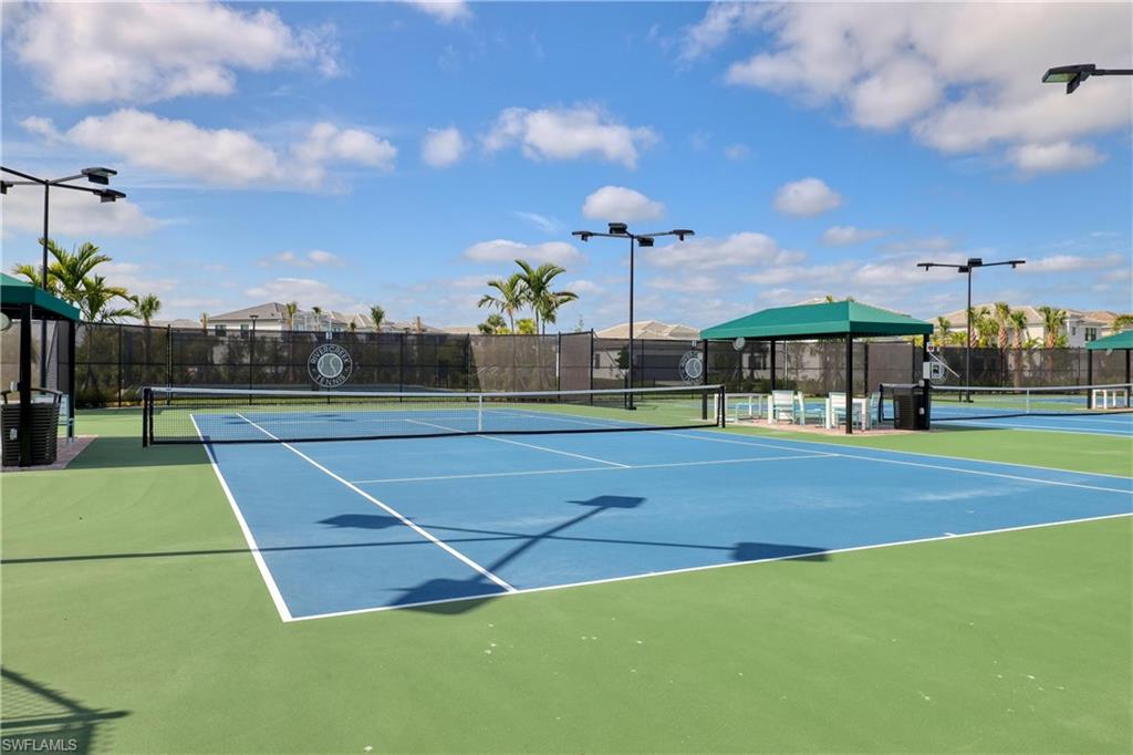 View of tennis court featuring fence and community basketball court