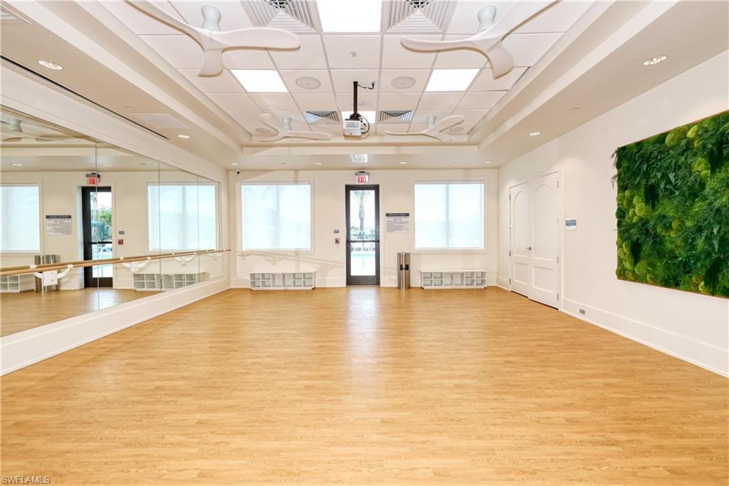 Exercise room featuring a tray ceiling and light wood-style floors