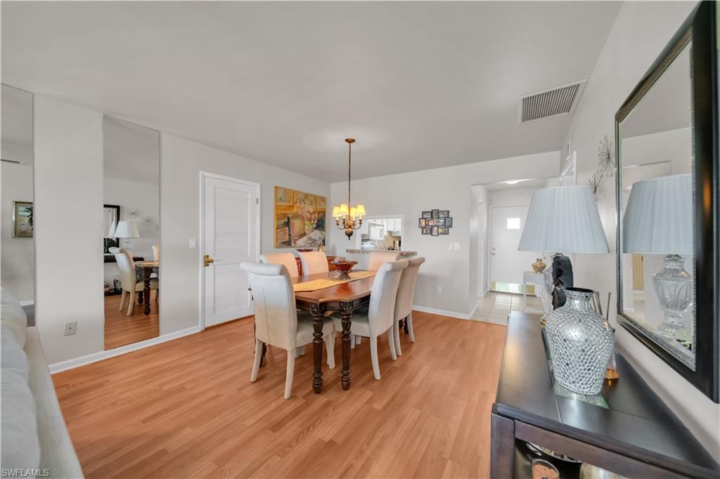 Dining area featuring wood-finish flooring, a built-in ceiling light fixture, white interior doors, and decorative wall mirrors