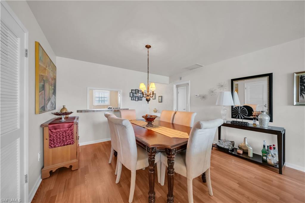 Dining area featuring warm wood-finish flooring, a pass-through window with a countertop, and recessed lighting