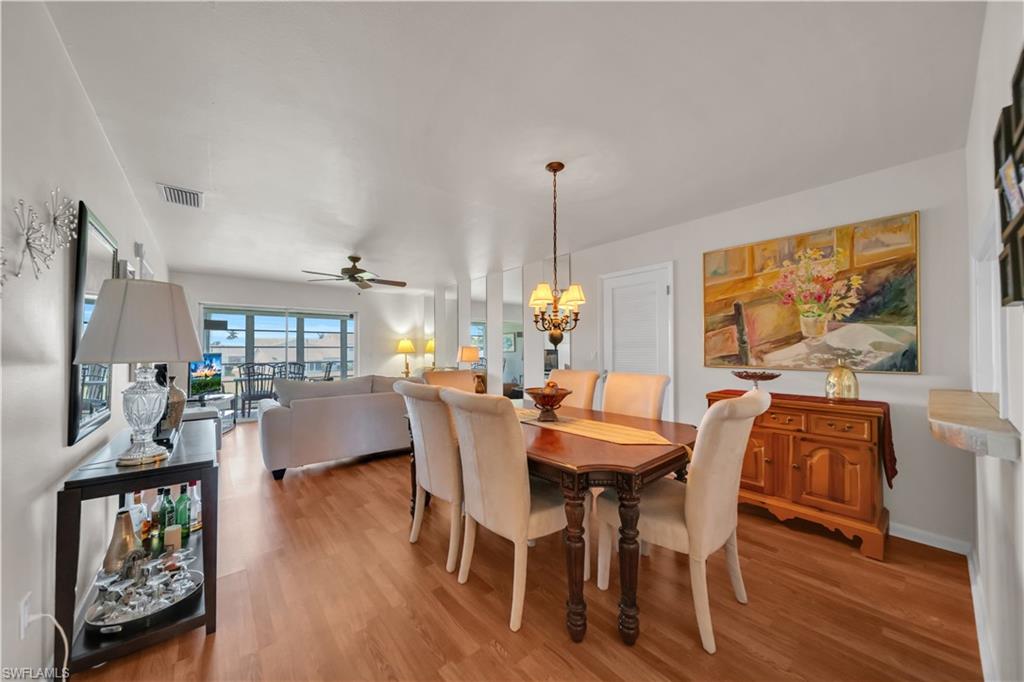 Dining area with wood-finish flooring, featuring a chandelier, and a white paneled door