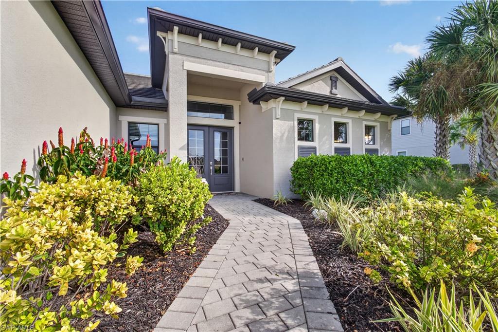 Stucco exterior with a paver walkway, double front entry doors, and established landscaping