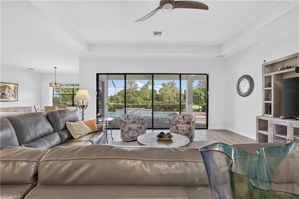 Tray ceiling with ceiling fan, expansive sliding glass doors, engineered wood flooring, built-in entertainment center, and recessed lighting