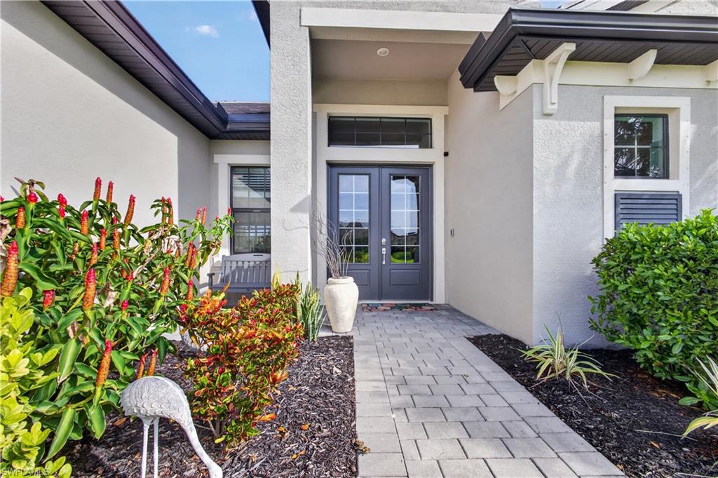 Entryway featuring double doors with transom window, paver walkway, stucco exterior, and integrated exterior lighting