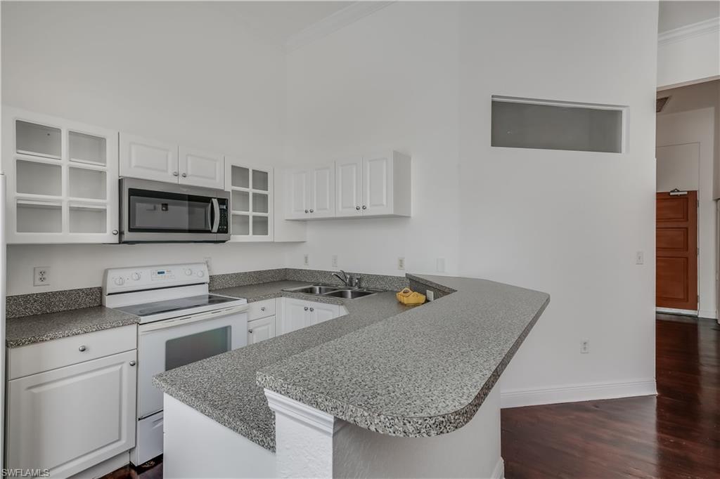 Kitchen with white range with electric cooktop, white cabinets, sink, and dark wood-type flooring