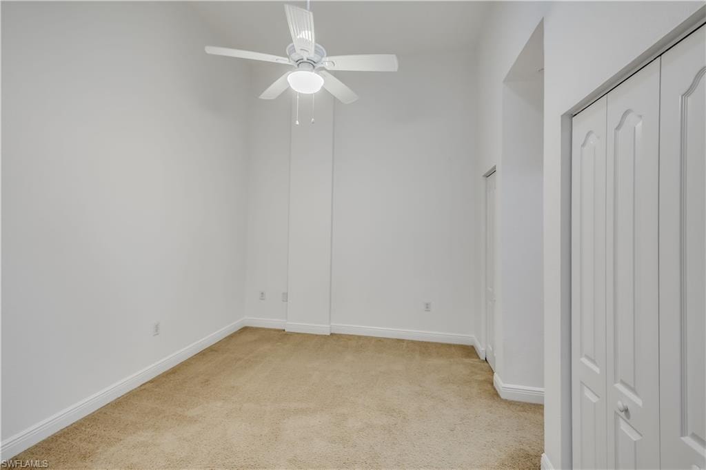 Unfurnished bedroom with ceiling fan and light colored carpet