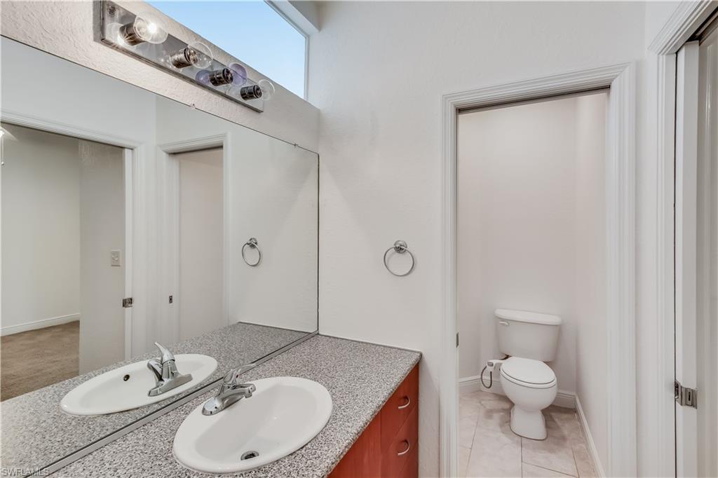 Bathroom featuring tile flooring, toilet, and large vanity