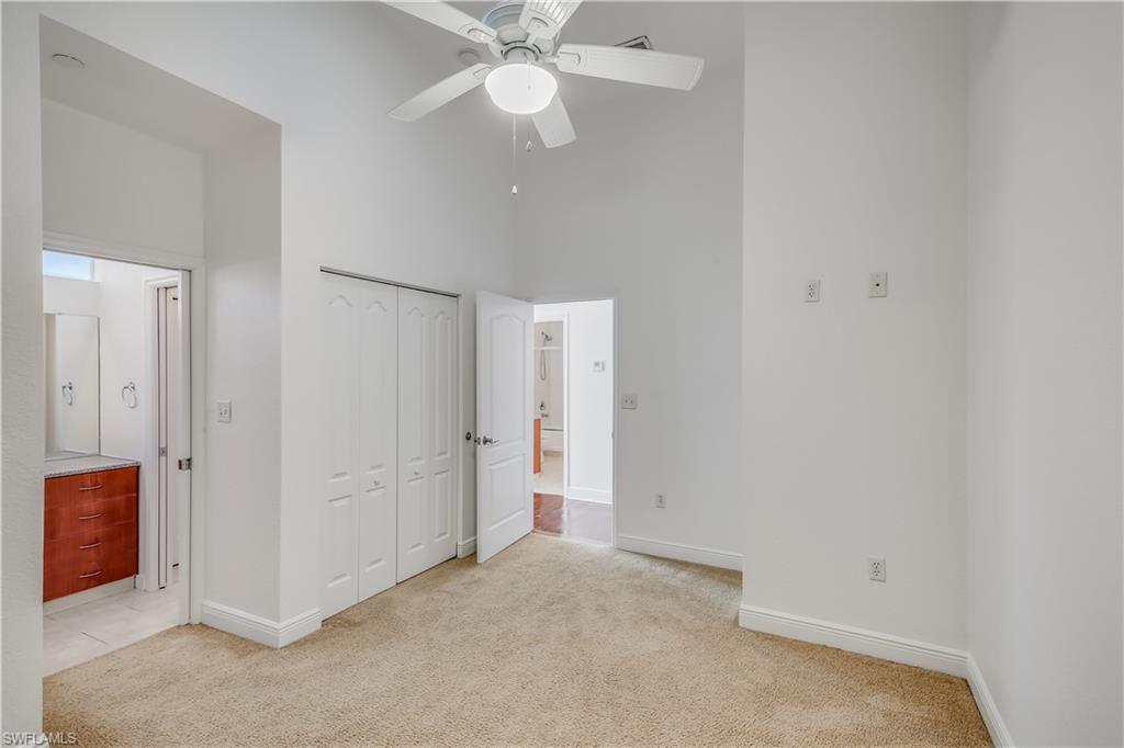 Unfurnished bedroom with a towering ceiling, a closet, ceiling fan, and light colored carpet