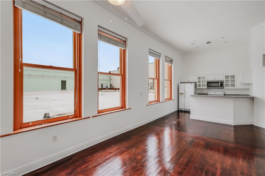 Unfurnished living room featuring dark hardwood / wood-style floors and crown molding