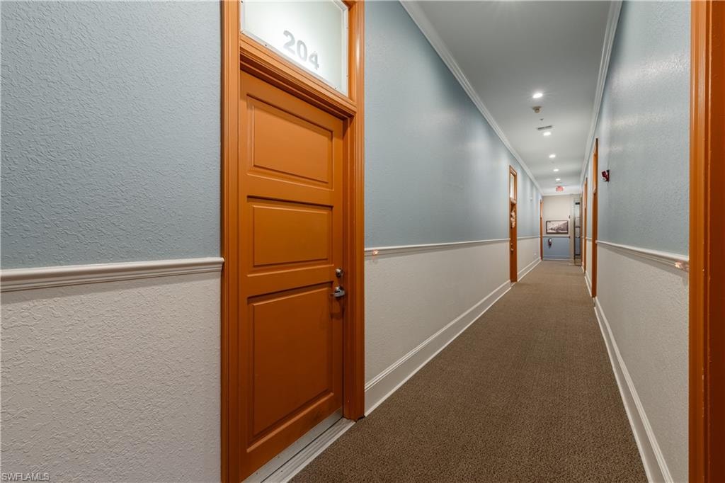 Hallway with ornamental molding and carpet