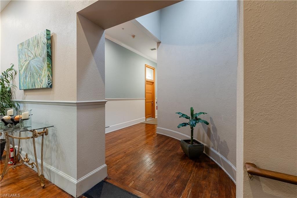 Corridor with hardwood / wood-style floors and crown molding