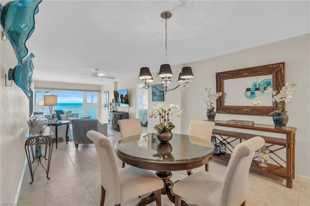 Open-concept living area featuring a dining space with a dark wood-finish table, a coordinating chandelier, and tile flooring
