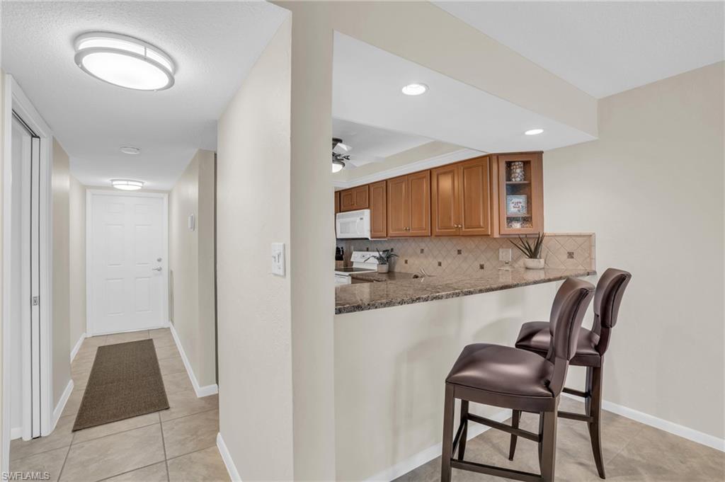Kitchen pass-through with a stone countertop and light wood cabinetry