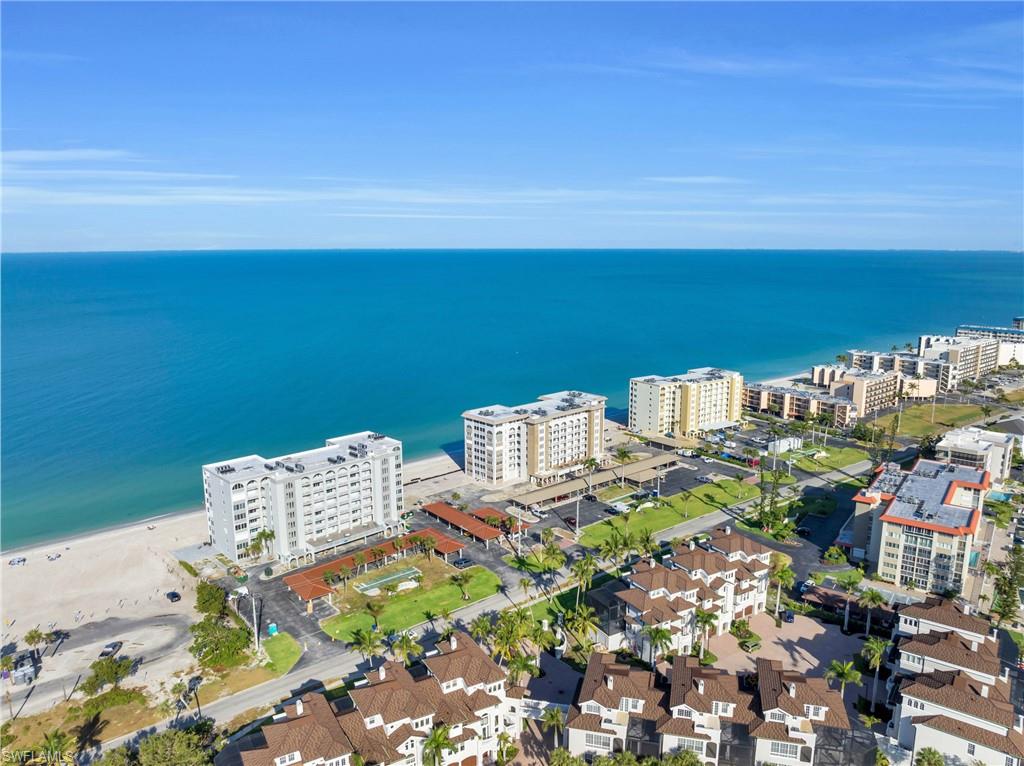 Expansive coastline featuring a sandy beach, clear blue water, and multiple waterfront residential buildings
