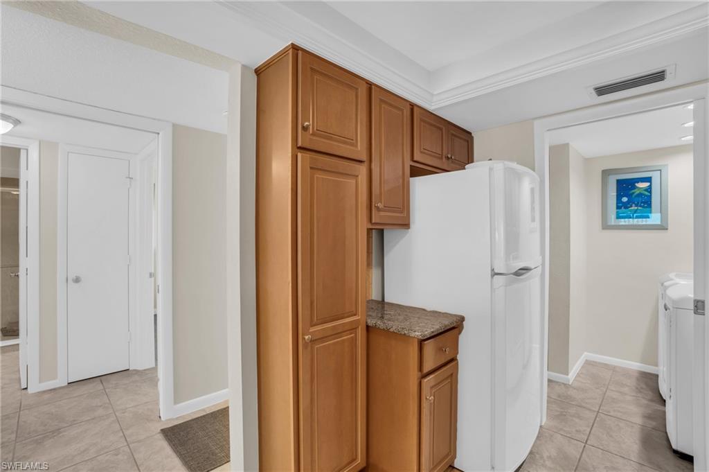 Kitchenette area featuring wood cabinetry, stone-look countertop, and tile flooring