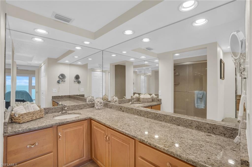 Dual sink vanity featuring light wood-finish cabinetry and stone countertops