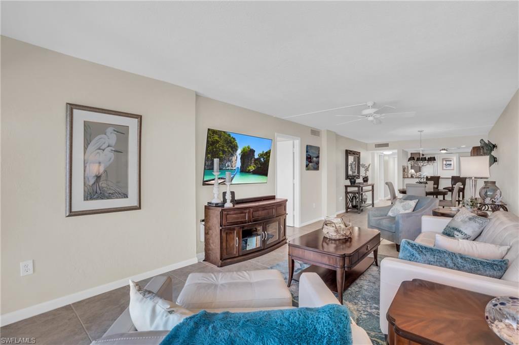 Spacious living area featuring neutral wall tones, tile flooring, and ceiling fan