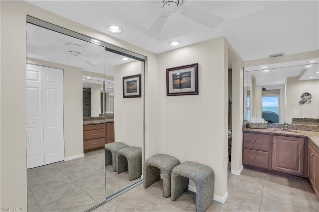 Mirrored wardrobe doors reflecting a ceiling fan, recessed lighting, and tile flooring